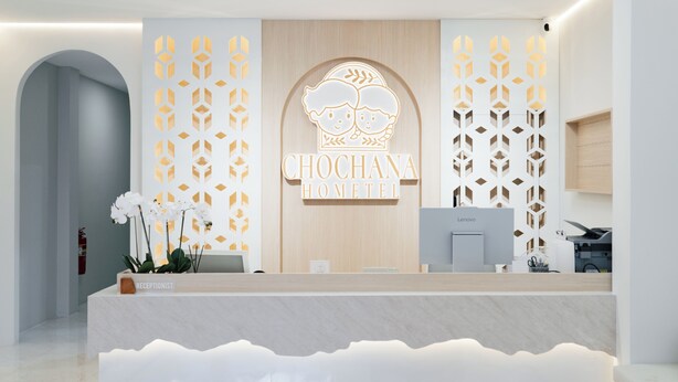 A reception desk with a logo, a receptionist sign, and a Lenovo computer.