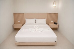 A hotel room with a large bed, two bedside tables, a wall-mounted light, and a phone on one of the tables. - Chochana Hometel Phuket Old Town (Phuket)