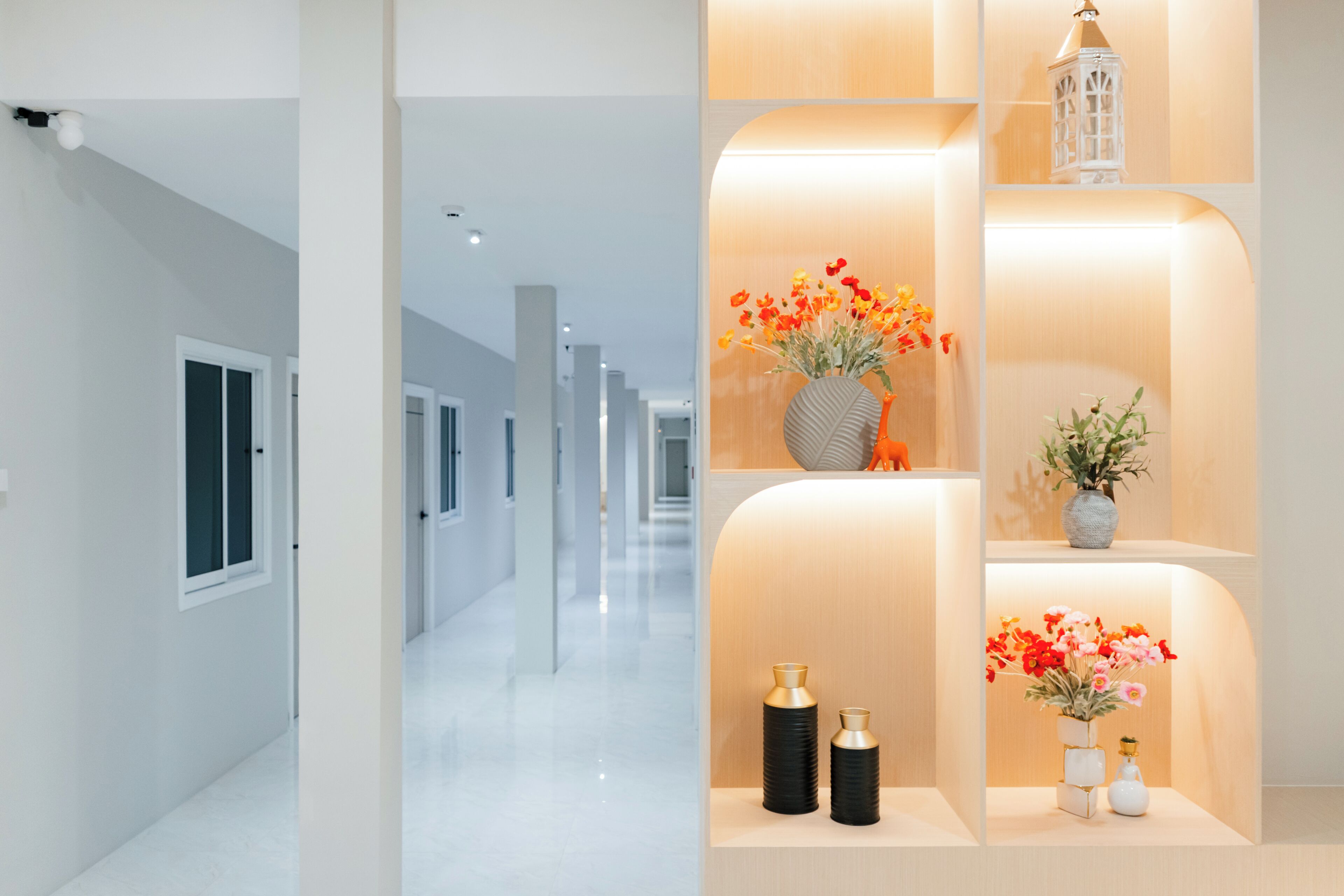 Un pasillo moderno de hotel, de diseño largo y recto, con varias paredes blancas, puertas y un pasillo central.
