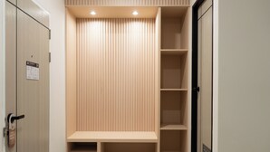 A walk-in closet with a bench, shelves, and a door with a fire escape plan sign.
