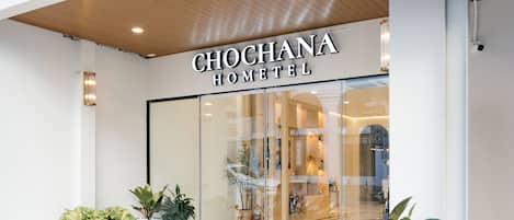 The exterior of Chochana Hotel with a glass facade, potted plants, and a clear view into the interior.