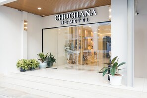Fachada de vidrio del hotel Chochana, con plantas en macetas y una vista despejada al interior.