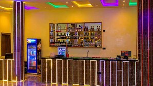 Zona de bar con mostrador, estanterías llenas de botellas y una máquina expendedora.