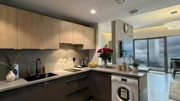 A modern kitchen with dark cabinetry, a built-in washing machine, and a large window offering a view.