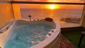 Un jacuzzi con vistas a la puesta de sol sobre el océano.