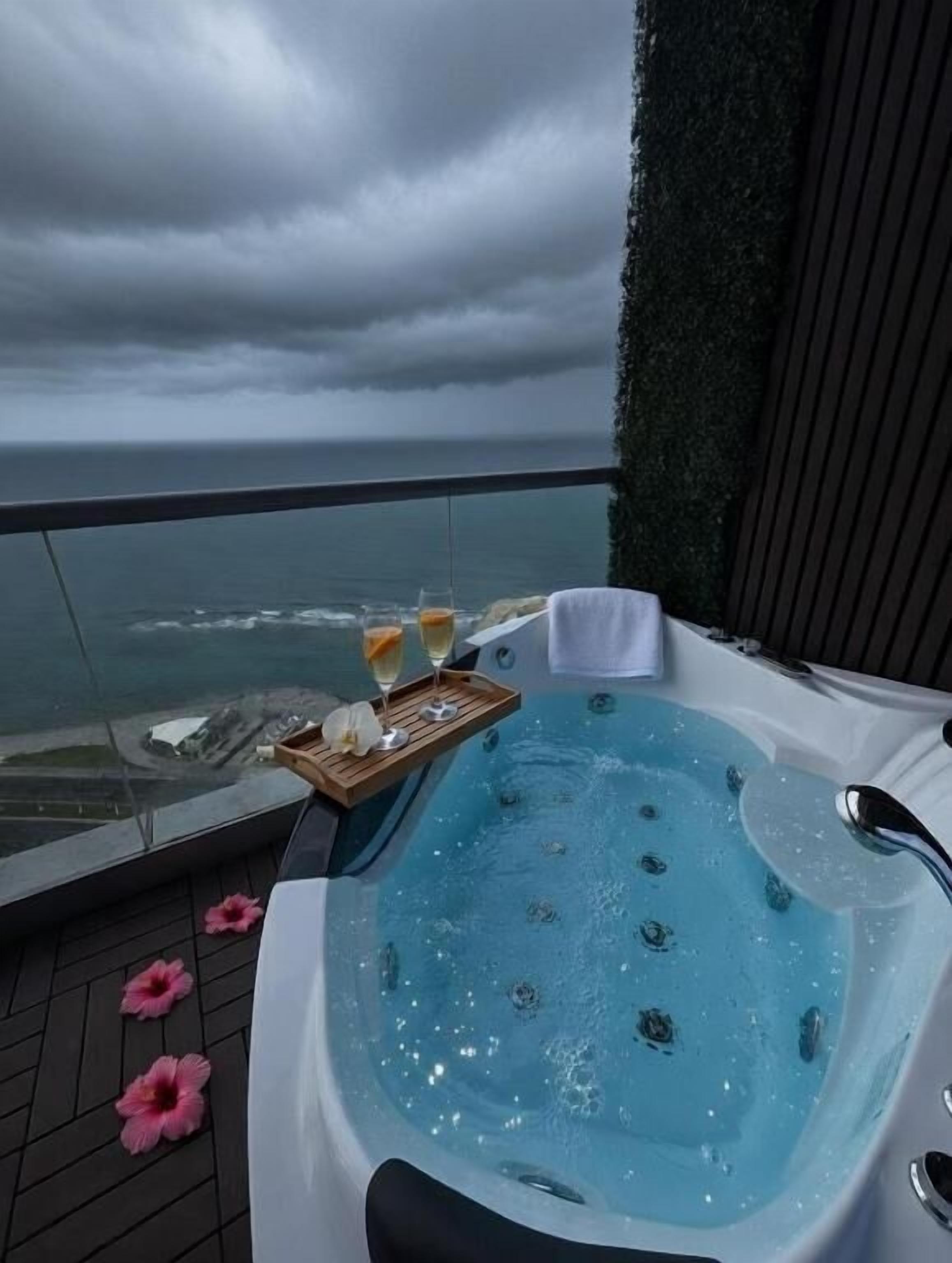 A hot tub on a balcony with a view of the ocean.