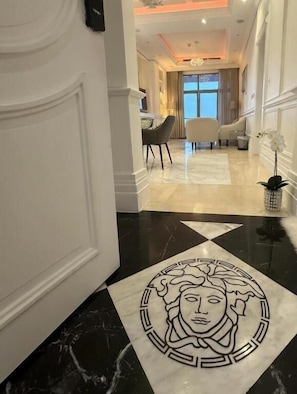A hotel hallway with a marble floor, a decorative pattern, and a view into a dining area. - Damac Al-Corniche Jeddah Tower (Jeddah)