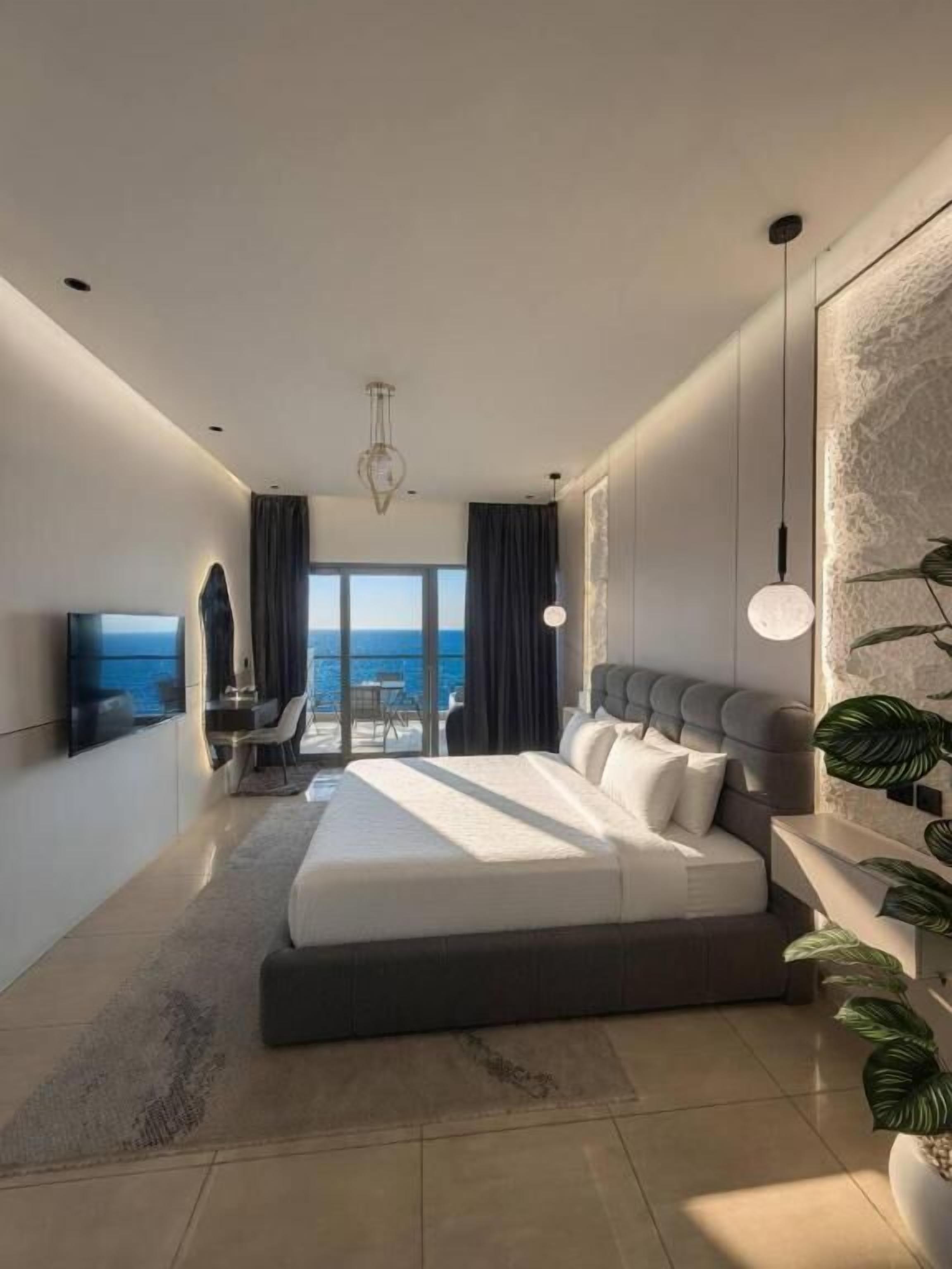 Una habitación de hotel moderna con una cama grande, un televisor de pantalla plana, un balcón con vistas y un comedor.