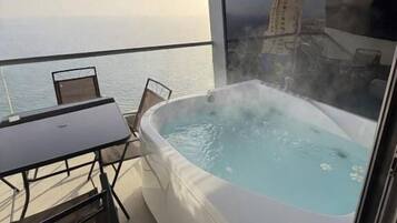Un balcón con jacuzzi, una mesa y sillas.