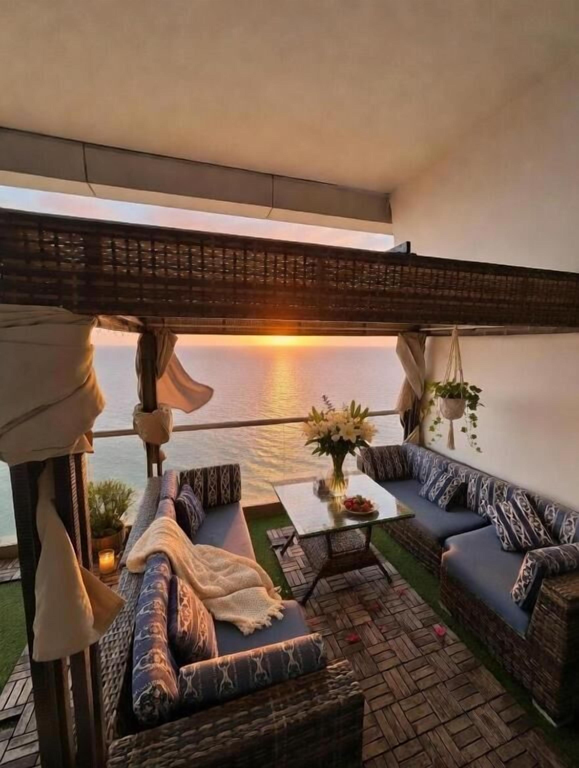 A balcony with a sofa, a small table, and a hanging plant.
