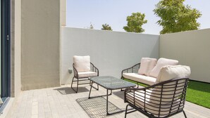 An outdoor patio with a sofa, two chairs, and a small table. - Bloomfields 2BRplus Maid in Noya Viva  (Abu Dhabi)
