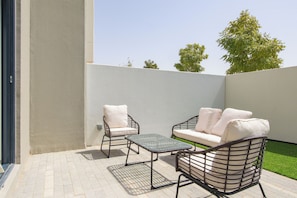 Eine Terrasse im Freien mit einer Couch, zwei Stühlen und einem kleinen Tisch.