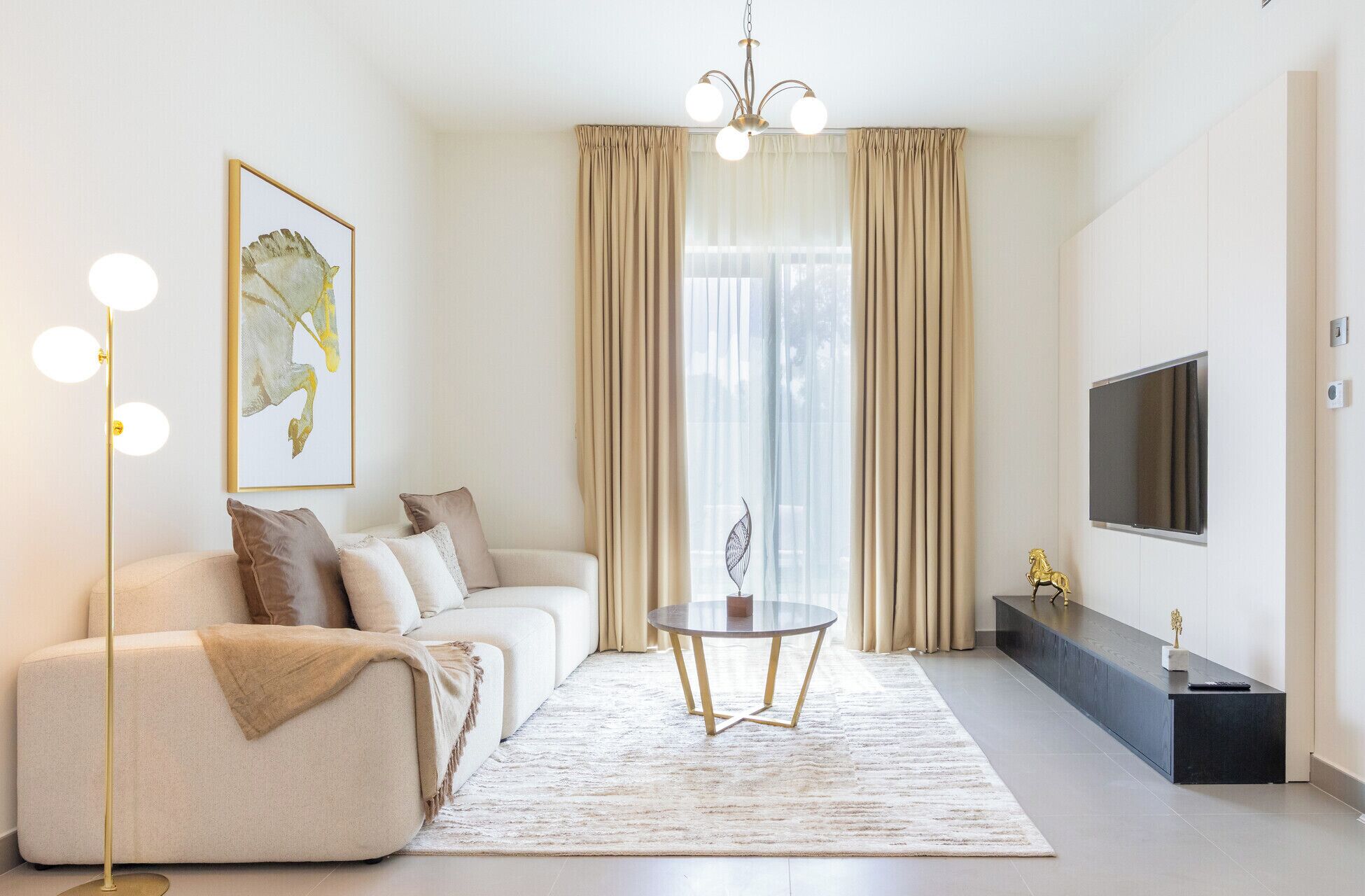 Un salon moderne comprenant un canapé, une table basse, un lampadaire, un téléviseur et une grande fenêtre avec des rideaux.