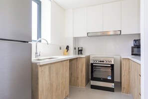 Eine kompakte Küche mit Einbauofen, Kaffeemaschine und Mikrowelle.
