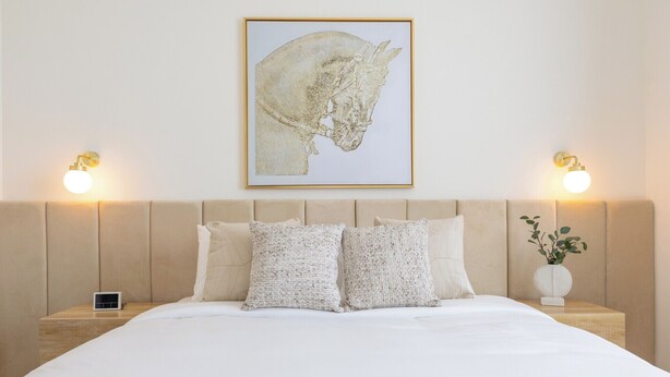 A hotel room with a bed, two bedside tables, a nightstand, a framed artwork, and wall-mounted lights. - Bloomfields 2BRplus Maid in Noya Viva  (Abu Dhabi)