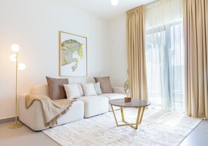A modern living room with a sofa, a round coffee table, and a floor lamp. - Bloomfields 2BRplus Maid in Noya Viva  (Abu Dhabi)