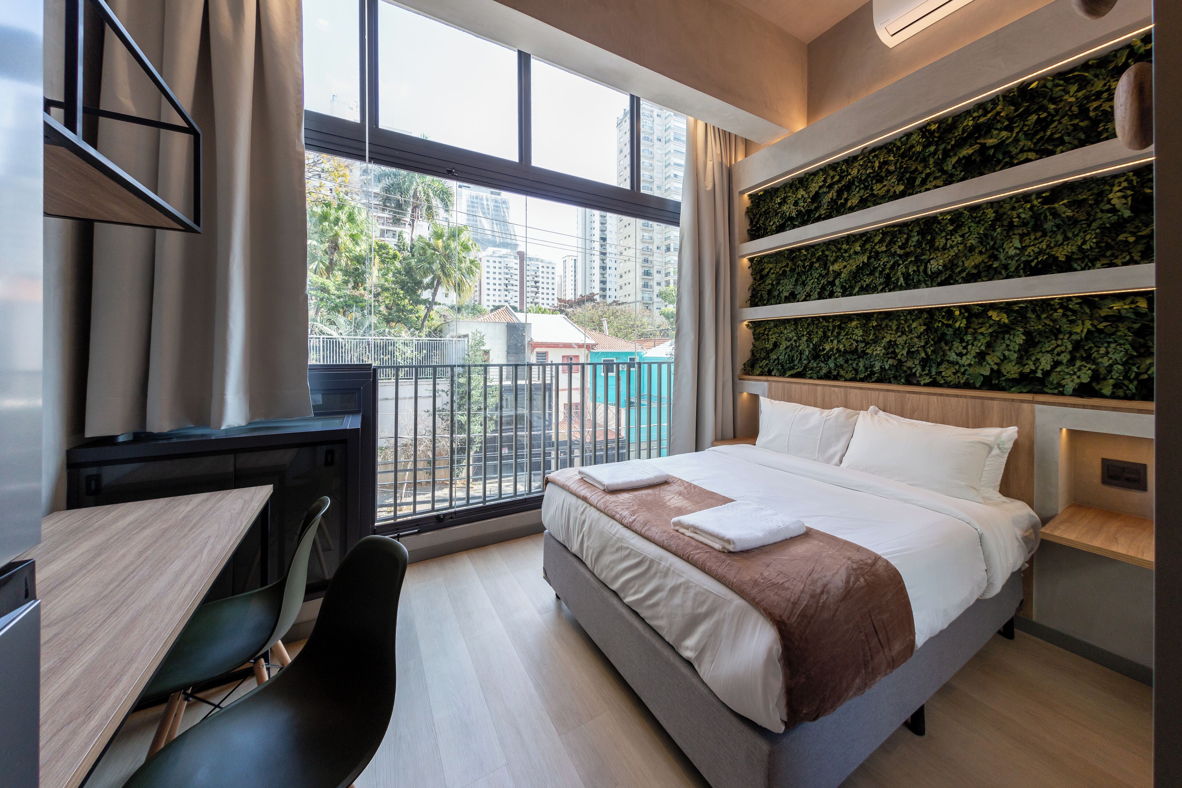 Habitación de hotel moderna con una cama grande, un escritorio y vistas a la ciudad.