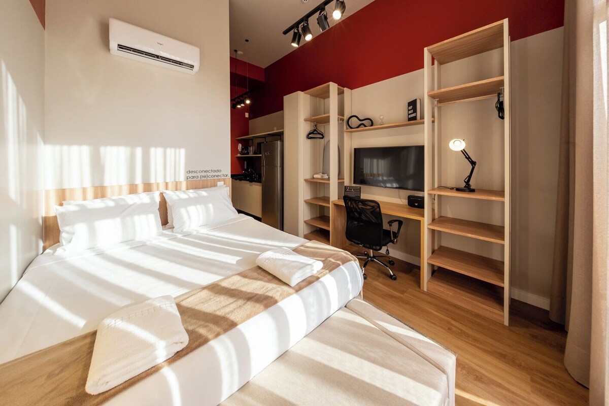Ein Hotelzimmer mit Bett, Schreibtisch, Stuhl, Fernseher und Kleiderschrank.
