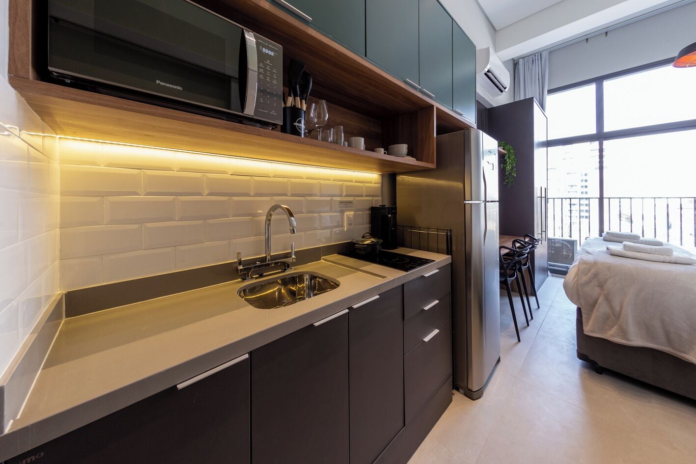 A modern kitchen with a built-in microwave, stainless steel sink, and a dining area with a balcony view.
