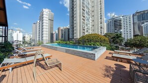 Un espace piscine aménagé sur le toit, avec des chaises longues et une piscine.