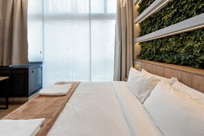A hotel room with a bed, a bedside table, a nightstand, and a wall-mounted plant. - Aimbere by Bhomy (São Paulo)