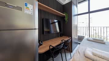 Uma kitchenette moderna com frigorífico embutido, uma TV de ecrã plano e uma mesa de jantar de madeira com cadeiras.