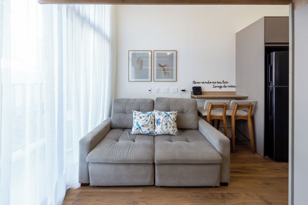 A living room with a sofa, two chairs, a small table, and a kitchen area in the background.