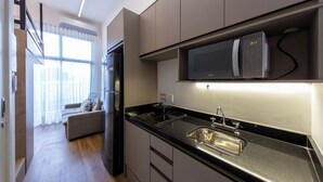 Une cuisine moderne dotée d’un four à micro-ondes encastré, d’un évier en acier inoxydable et d’un plan de travail noir.