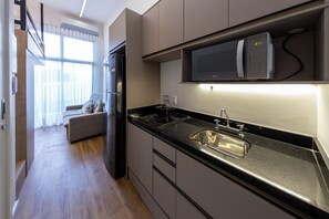 Eine moderne Küche mit integriertem Mikrowellenherd, Spüle aus Edelstahl und einer schwarzen Arbeitsplatte.