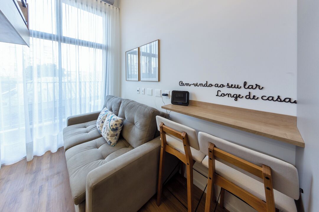 A modern living room with a sofa, chairs, a wooden shelf, and a wall-mounted TV.