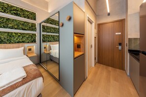 Habitació d'hotel moderna amb un llit, un mirall, un armari i una paret verda.