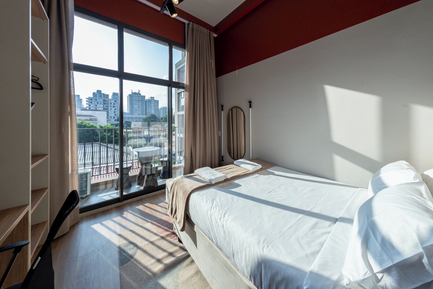 Une chambre d’hôtel avec une grande fenêtre, un lit, une table de chevet et une armoire.