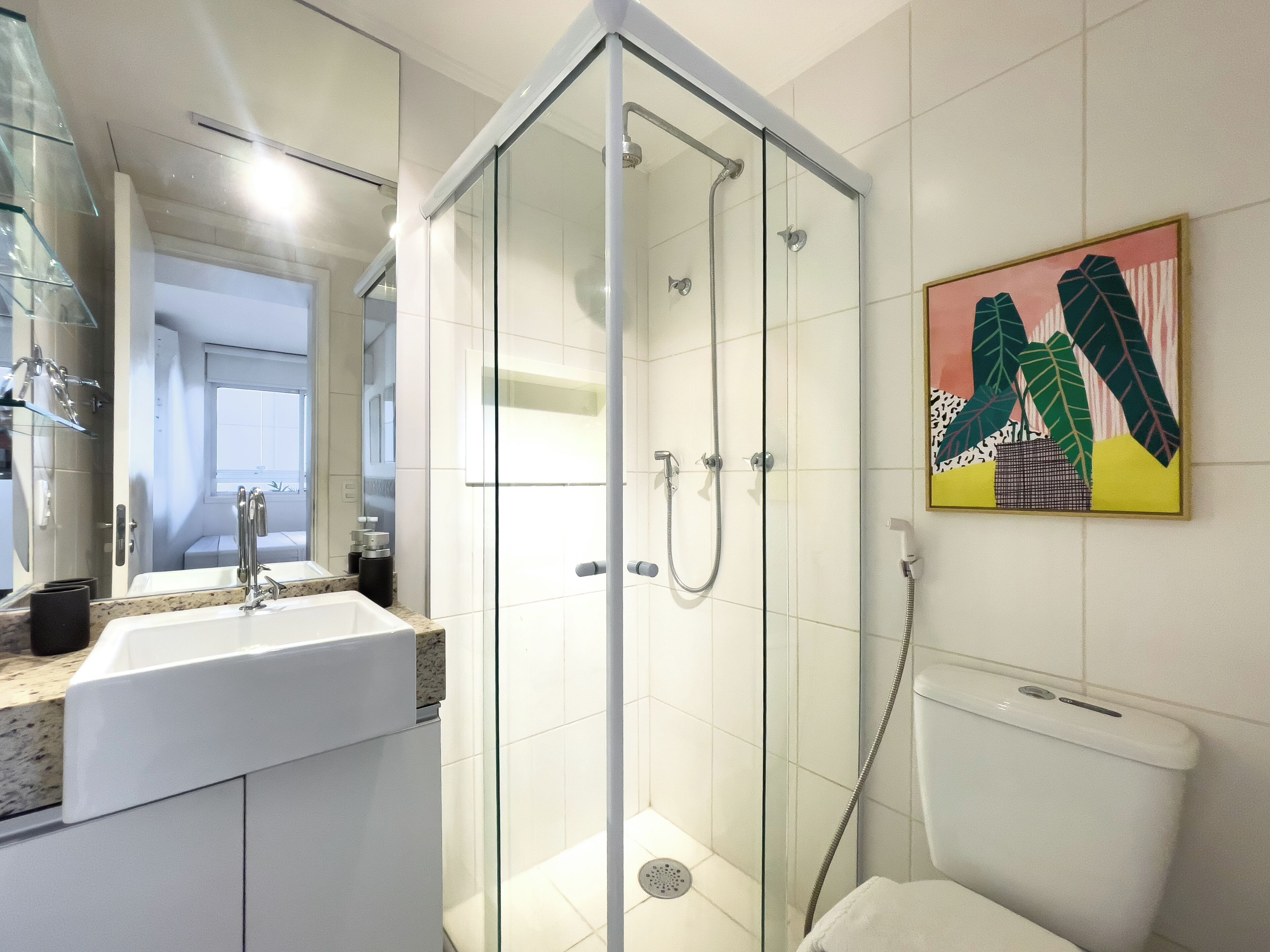 A modern bathroom with a glass-enclosed shower, a sink with a marble countertop, and a toilet.