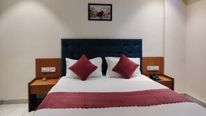 A neatly made bed with a dark headboard, two bedside tables, and a wall-mounted picture.