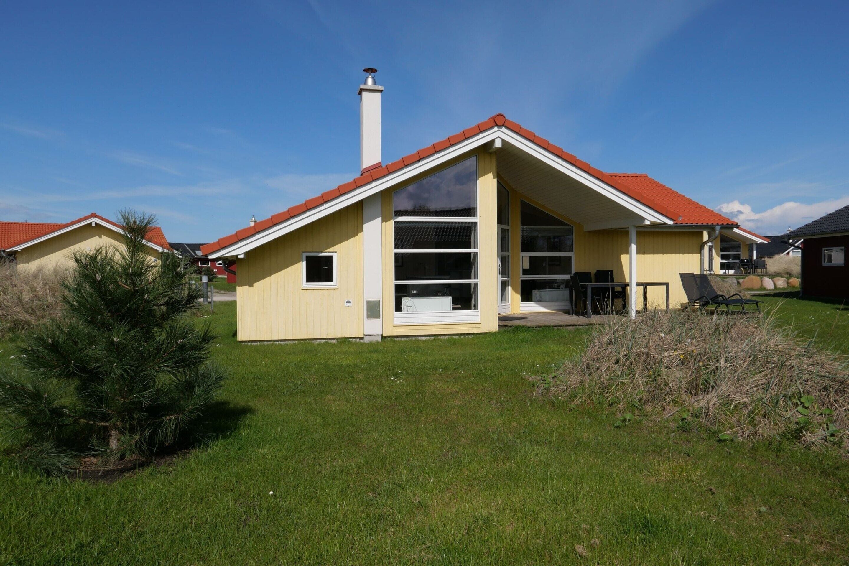 A single-story house with a red roof, large windows, and a chimney.