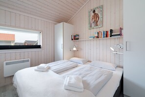 Ein Schlafzimmer mit zwei Betten, einem Fenster, einer Heizung, einem Bücherregal und einem Bild an der Wand.