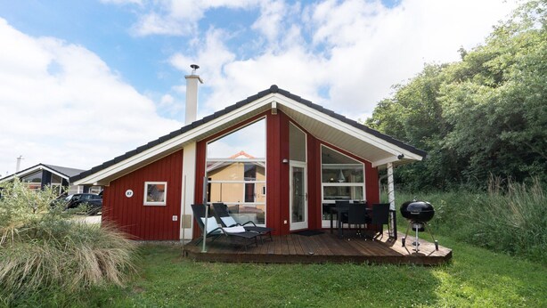 A red cabin with a deck, a chimney, and a grill. - Urlaub in der Baltischen Natur fur 6 Personen (Grossenbrode)