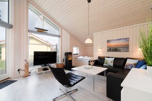 Ein modernes Wohnzimmer mit Kamin, Flachbildfernseher, einer Couch und einem Couchtisch.
