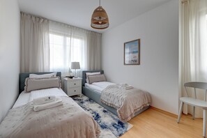 Ein Schlafzimmer mit zwei Betten, einem Nachttisch, einer Lampe, einem Stuhl und einem Bild an der Wand.