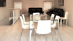 A spacious living area with a high ceiling, a glass-top dining table surrounded by chairs, and a black leather sofa. - Budello di Alassio, spacious apartment 30 meters from the beach, garage included (Alassio)