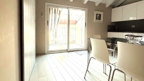 A modern kitchen with white cabinets, a black countertop, and a glass dining table with chairs. - Budello di Alassio, spacious apartment 30 meters from the beach, garage included (Alassio)