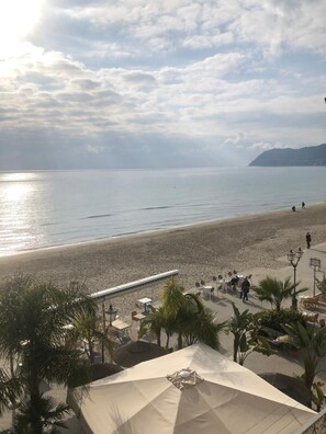 A beachside view with a clear sky, calm sea, and a few people walking. - Budello di Alassio, spacious apartment 30 meters from the beach, garage included (Alassio)