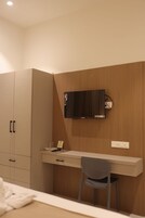 A bedroom with a bed, a desk, a chair, and a wardrobe.