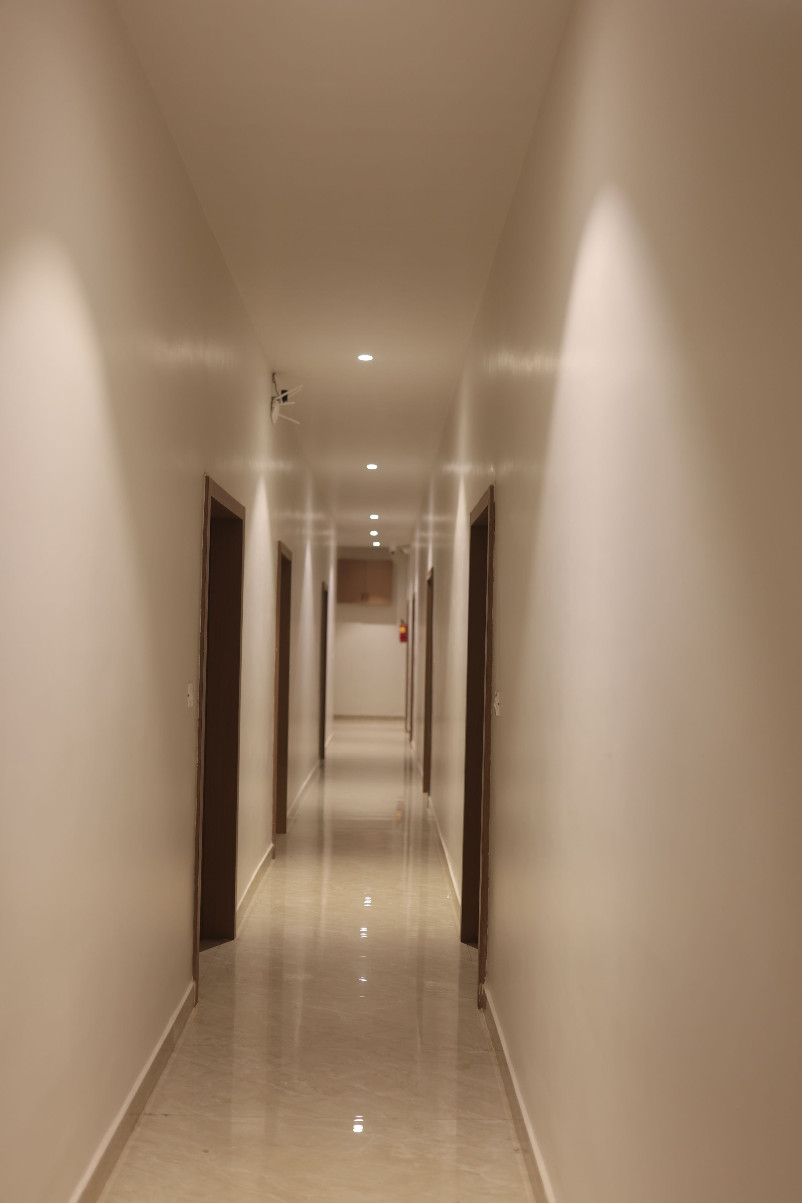 Un pasillo largo y estrecho con puertas a ambos lados, que conduce a habitaciones.