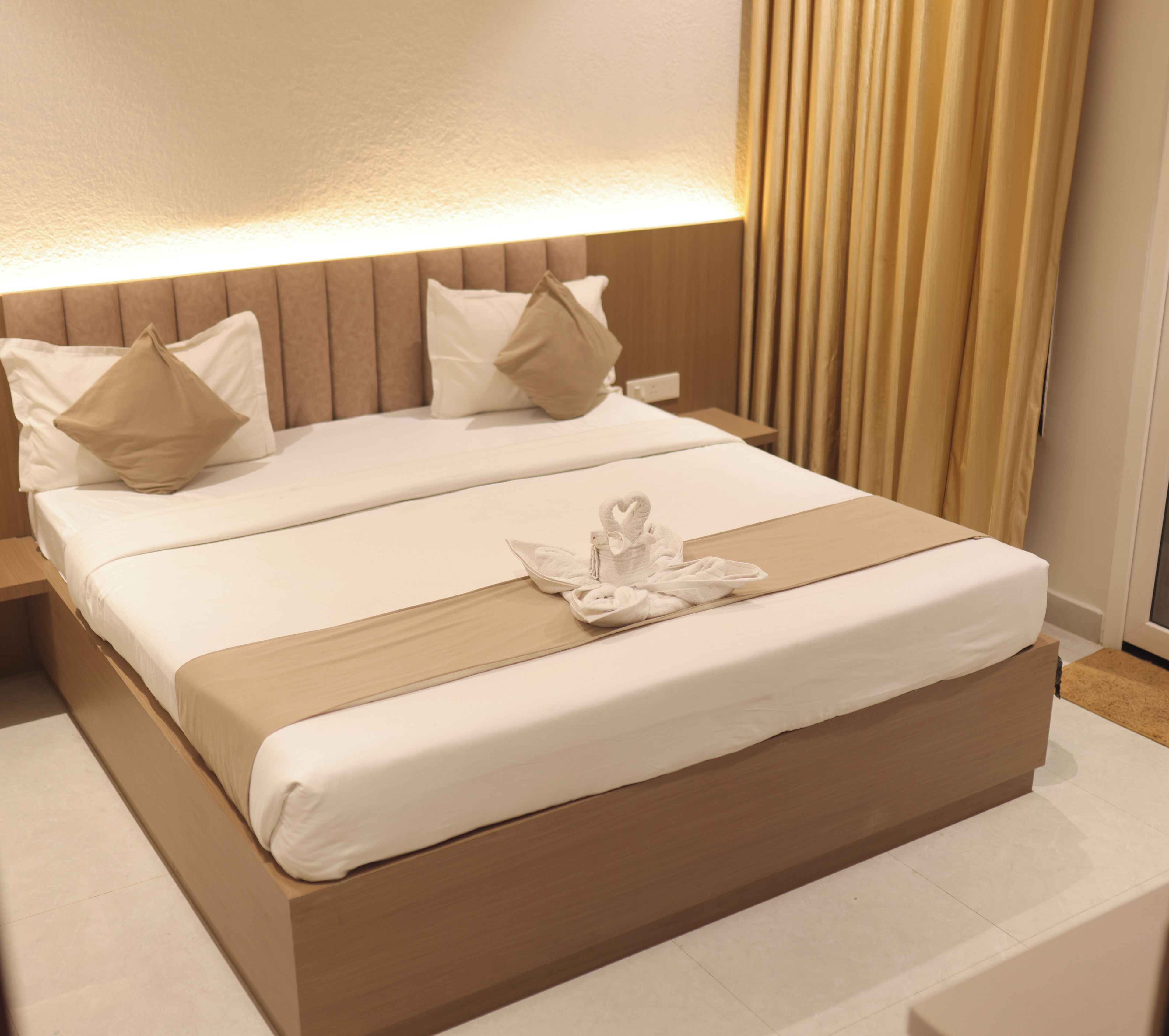 A hotel room with a large bed, a headboard with vertical lines, and a bedside table.