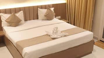 A hotel room with a large bed, a headboard with vertical lines, and a bedside table.