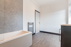 Un baño moderno con bañera, toallero y puerta.