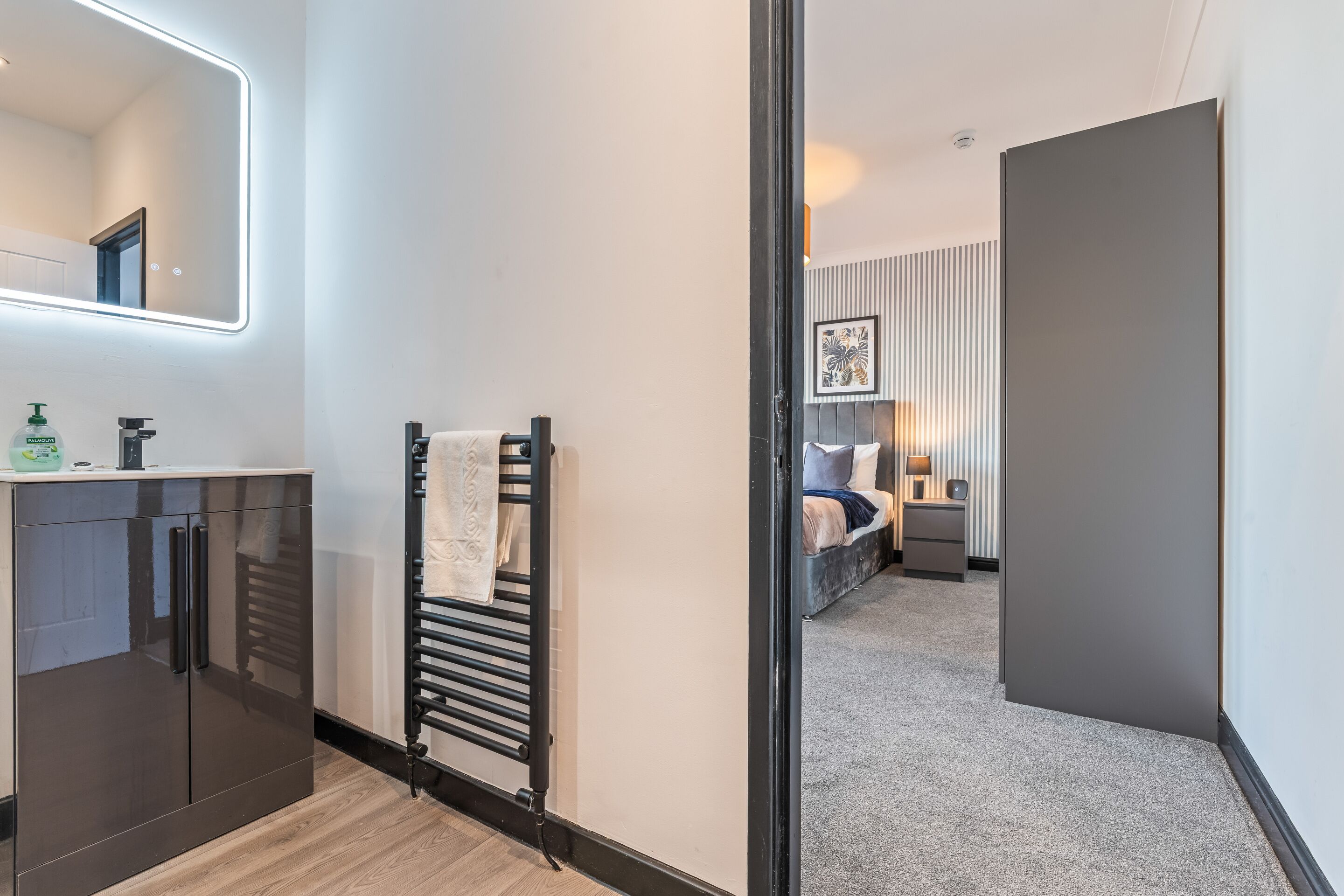 A modern bathroom with a mirror, sink, and towel rack.