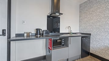 A compact kitchen with a built-in oven, a coffee maker, and a kettle.