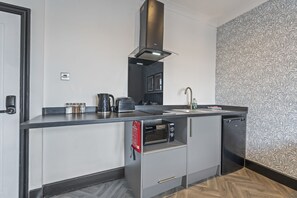 Una cocina compacta con horno integrado, cafetera y hervidor.